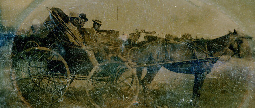 Degraded sepia photograph of three Black men in a horse drawn wagon