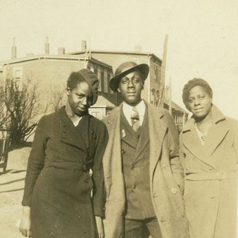 Black and white photo of three black people dressing in coats in 1930